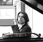 Rafael Torralvo headshot sitting at grand piano with violin
