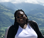 Christy Atangana Headshot smiling mountains in the background