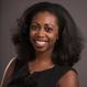 Tiffany Agard headshot standing in front of gray background smiling